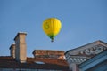 Yellow colorful hot air balloon flying in blue sky over roofs of city Royalty Free Stock Photo