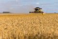 Yellow combine harvester on a wheat field with blue sky Royalty Free Stock Photo