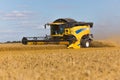 Yellow combine harvester on a wheat field with blue sky Royalty Free Stock Photo