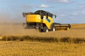 Yellow combine harvester on a wheat field with blue sky Royalty Free Stock Photo