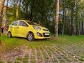 Yellow compact car Kia Picanto parked in eco friendly parking with protecting grass covering. City carpark area with grass lawn Royalty Free Stock Photo