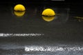 Yellow concrete hemispheres on black wet asphalt.