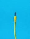 Yellow connector with an audio output wire on a blue background. Flat lay