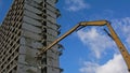 Yellow crane demolishing a stripped down apartment building