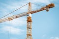 Yellow construction crane with cabin against blue sky. Lifting of cargo. Construction machinery concept, modern technology Royalty Free Stock Photo