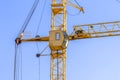 Yellow construction crane with cabin close-up against blue sky background. Concept of lifting of cargo, construction Royalty Free Stock Photo