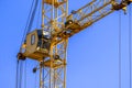 Yellow construction crane with cabin close-up against blue sky background. Concept of lifting of cargo, construction Royalty Free Stock Photo