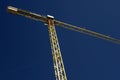 Yellow construction crane reaching clear blue sky Royalty Free Stock Photo