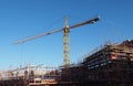 Construction crane working on a large modern apartment development with scaffolding with blue sky and sunlight