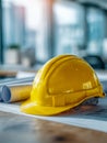 Yellow construction helmet resting on architectural blueprints with rolled plans in a bright office environment symbolizing Royalty Free Stock Photo