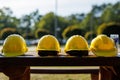 Yellow construction helmets lined up on wooden bench outdoors Royalty Free Stock Photo