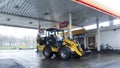 Yellow excavator construction vehicle refueling at a gas station in Germany
