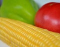 Yellow corn cobs, red tomato and green pepper lie on the table, close-up, traffic light colors Royalty Free Stock Photo