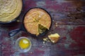 Yellow Cornbread in cast iron skillet on rustic wood table top view