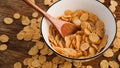 Yellow cornflakes in a white bowl. Wooden spoon in a bowl. Wood background Royalty Free Stock Photo