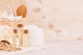 Yellow cosmetics oil, oatmeal cereals and white cream, bath accessories on beige wooden shelf, copy space.