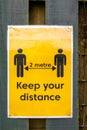 Yellow COVID-19 warning sign to keep 2 metre social distancing