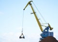 Yellow crane in cargo port translating coal. Industrial scene