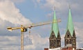 Yellow crane in front of two cathedral spires, blue sky, clouds