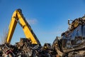 Yellow crane, stacked cars and motors at a dumpsite.