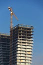 Crane on skyscraper construction site with windows reflecting sky Royalty Free Stock Photo