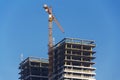 Crane on skyscraper construction site with windows reflecting sky Royalty Free Stock Photo