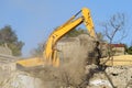Yellow crawler excavator demolishes dilapidated real estate for future construction of modern house Royalty Free Stock Photo