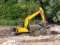 Yellow crawler excavator while working on a construction site. The machine lifted a bucket full of soil above the