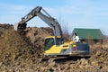 Yellow crawler excavator is working on dumping of soil