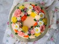 Yellow cream cake decorated with buttercream flowers - peonies, roses, chrysanthemums, carnations - on white wooden background. Royalty Free Stock Photo