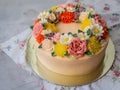 Yellow cream cake decorated with buttercream flowers - peonies, roses, chrysanthemums, carnations - on white wooden background. Royalty Free Stock Photo