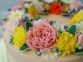 Yellow cream cake decorated with buttercream flowers - peonies, roses, chrysanthemums, carnations - on white wooden background. Royalty Free Stock Photo