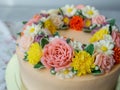 Yellow cream cake decorated with buttercream flowers - peonies, roses, chrysanthemums, carnations - on white wooden background. Royalty Free Stock Photo