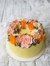 Yellow cream cake decorated with buttercream flowers - peonies, roses, chrysanthemums, scabiosa, carnations - on white wooden back Royalty Free Stock Photo