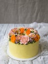 Yellow cream cake decorated with buttercream flowers - peonies, roses, chrysanthemums, scabiosa, carnations - on white wooden back Royalty Free Stock Photo