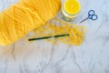 Yellow crochet yarn, hook and scissors with candle on neutral background Royalty Free Stock Photo