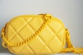 Yellow cross body bag. Ladies bright-colored handbag on gray background