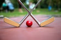 Yellow crossed iron rackets and a red ball at a minigolf court a