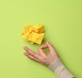 Yellow crumpled ball of paper and female hand on a green background Royalty Free Stock Photo