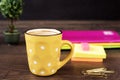 Yellow cup of coffee with white dots. Pretty pink office accessories - notebooks, gold pins, stickers, rubber and polka dot mug