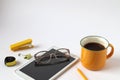 Yellow cup with hot tea, tablet, stationery pencil, glasses for vision on a white background, space for text, top view Royalty Free Stock Photo