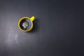 Yellow cup, mug of black coffee with clockwise stir flat lay on scrathed rough black background. Copy space for your text, image. Royalty Free Stock Photo