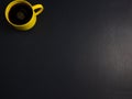 Yellow cup, mug of black coffee flat lay on scrathed rough black background. Copy space for your text, image or message.