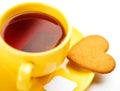 Yellow cup with tea bag and heart-shaped cookie