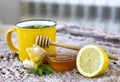 A yellow cup of tea on a beige blanket next to lemon, ginger, a spoonful of honey and green mint. Seasonal illnesses and colds. Royalty Free Stock Photo