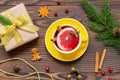 Yellow cup of tea with orange and spices near Christmas present and fir branch