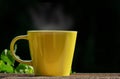 Yellow cup tea with vapor on wood table on black background Royalty Free Stock Photo