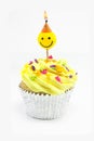 Yellow cupcake and smiley candle Royalty Free Stock Photo