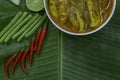 Yellow curry snapper fish with Lotus Stems, Southern Thai Spicy food and fresh vegetable in white dish on banana leaf / selective.
