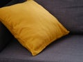 A yellow cushion on a gray couch